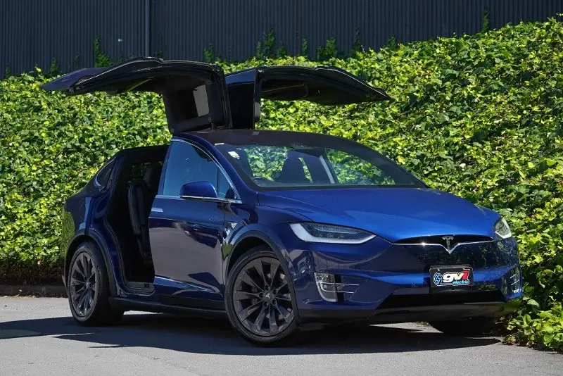 Blue Tesla Model X with its falcon wing doors open